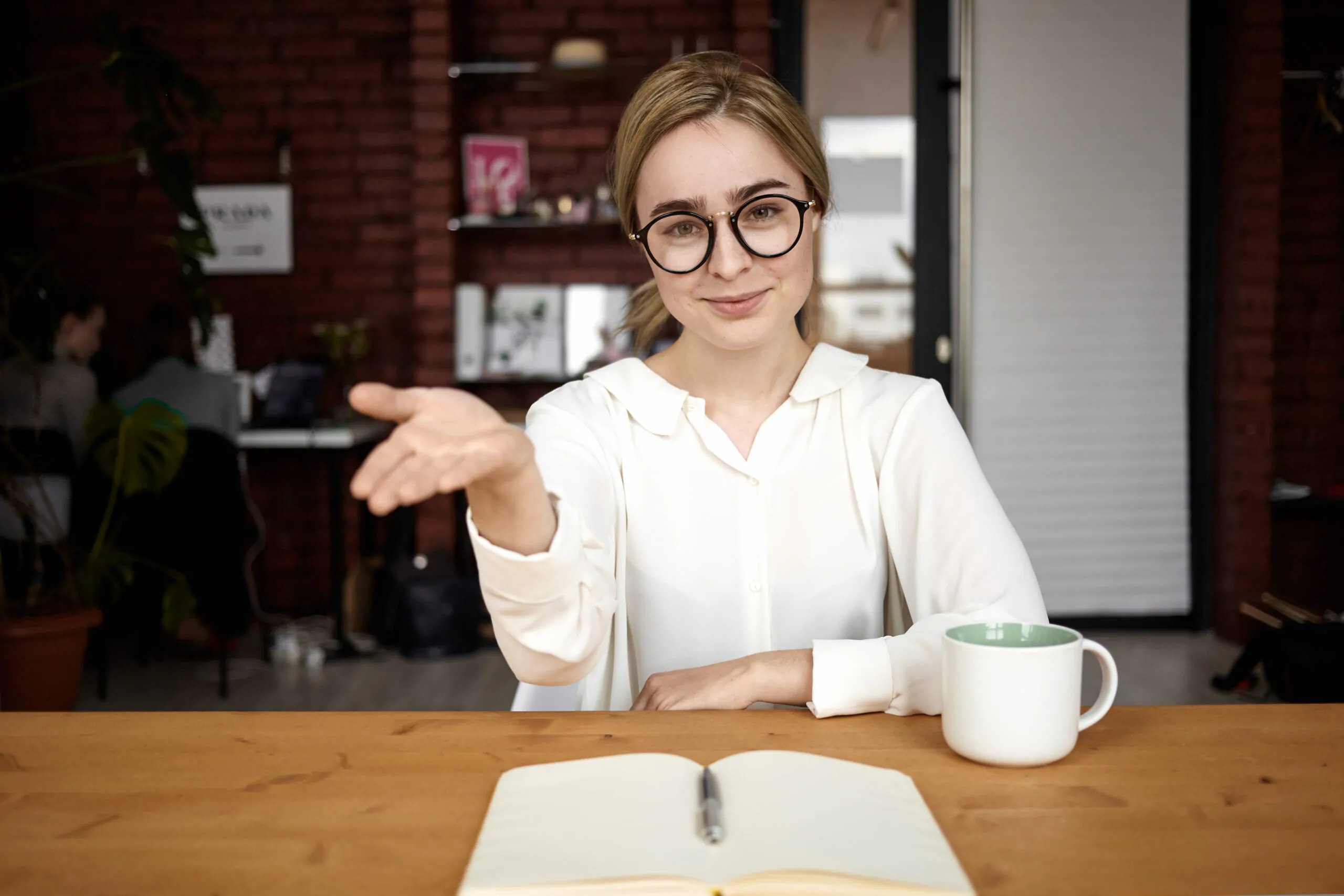 Polite human resources manager in eyewear sitting at her desk ex