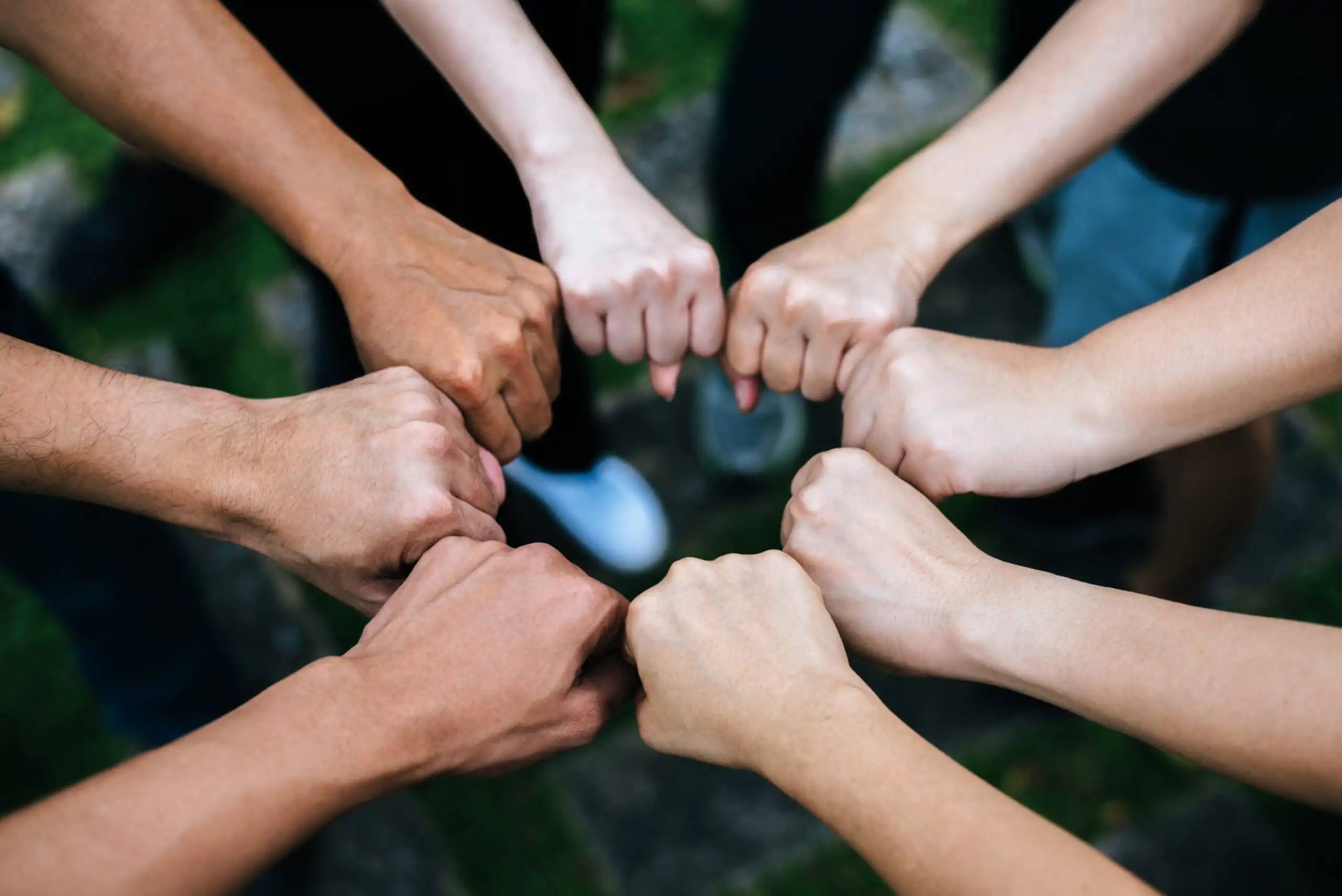 Close up of students standing hands making fist bump gesture. Inclusión laboral