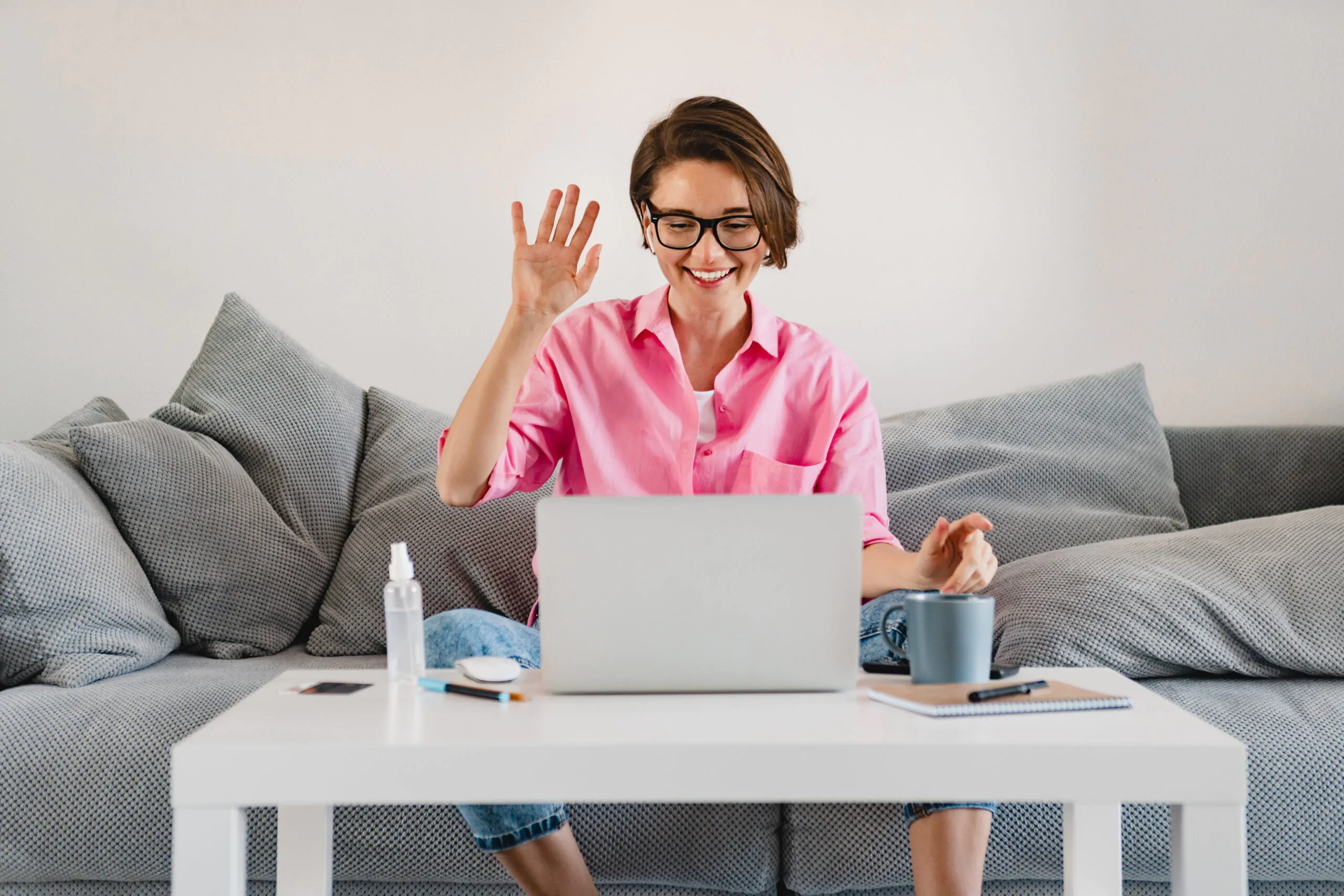 woman in pink shirt sitting relaxed on sofa at home at table working online on laptop Home office
