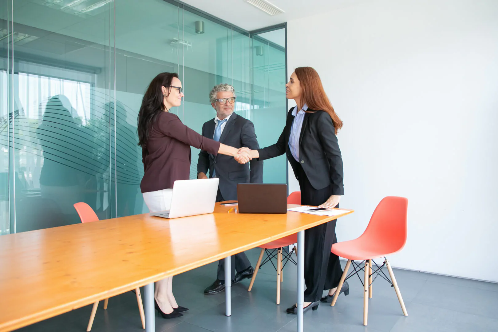 Smiling businesspeople standing and meeting in conference room Atracción de talento